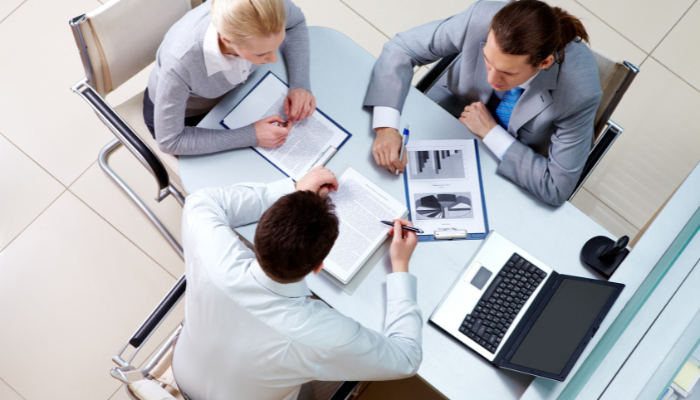 Homens ao redor de uma mesa conversando como converter os leads em clientes